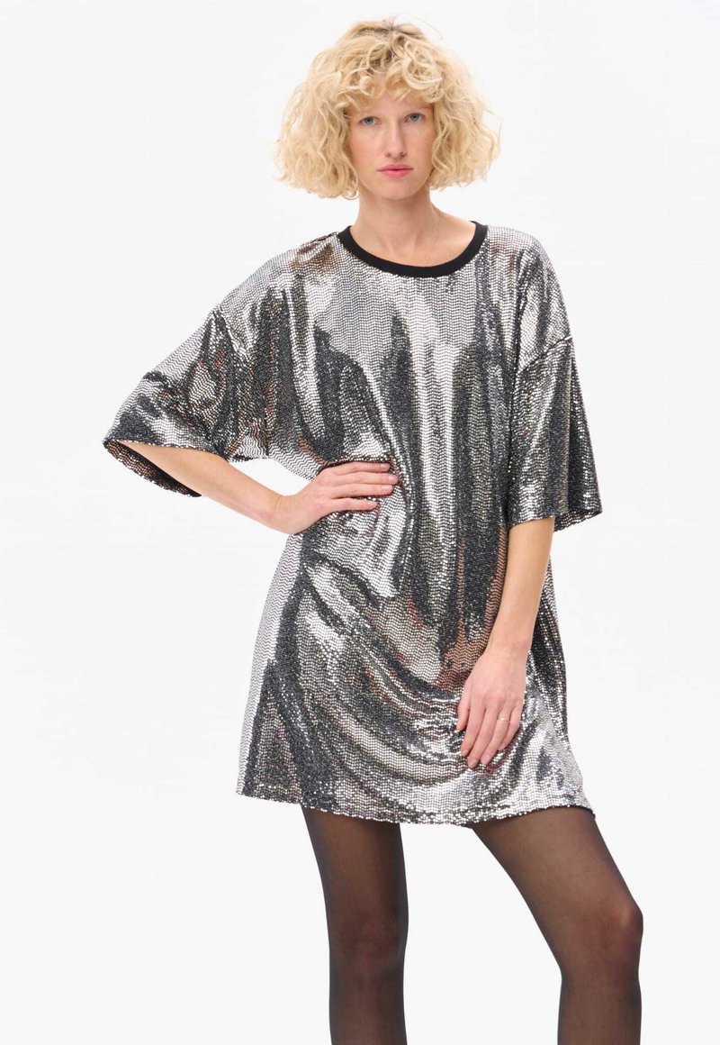 Robe mini en sequins argentés avec des manches surdimensionnées et un col noir, offrant une texture lisse et une surface réfléchissante brillante.