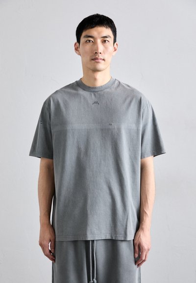 T-shirt in cotone grigio con collo rotondo e maniche corte, caratterizzato da un logo discreto sul petto e una vestibilità rilassata e squadrata.