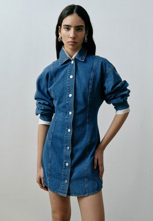 Jeanshemd jurk met een getailleerde pasvorm, oversized mouwen, een puntige kraag en knopen aan de voorkant. In diepblauw, met contrasterende witte accenten.