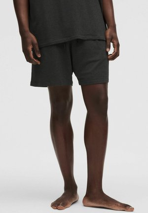 Dunkelgraue Baumwollshorts mit elastischem Bund, seitlichen Taschen und lockerem Schnitt, getragen mit einem passenden dunkelgrauen Oberteil.