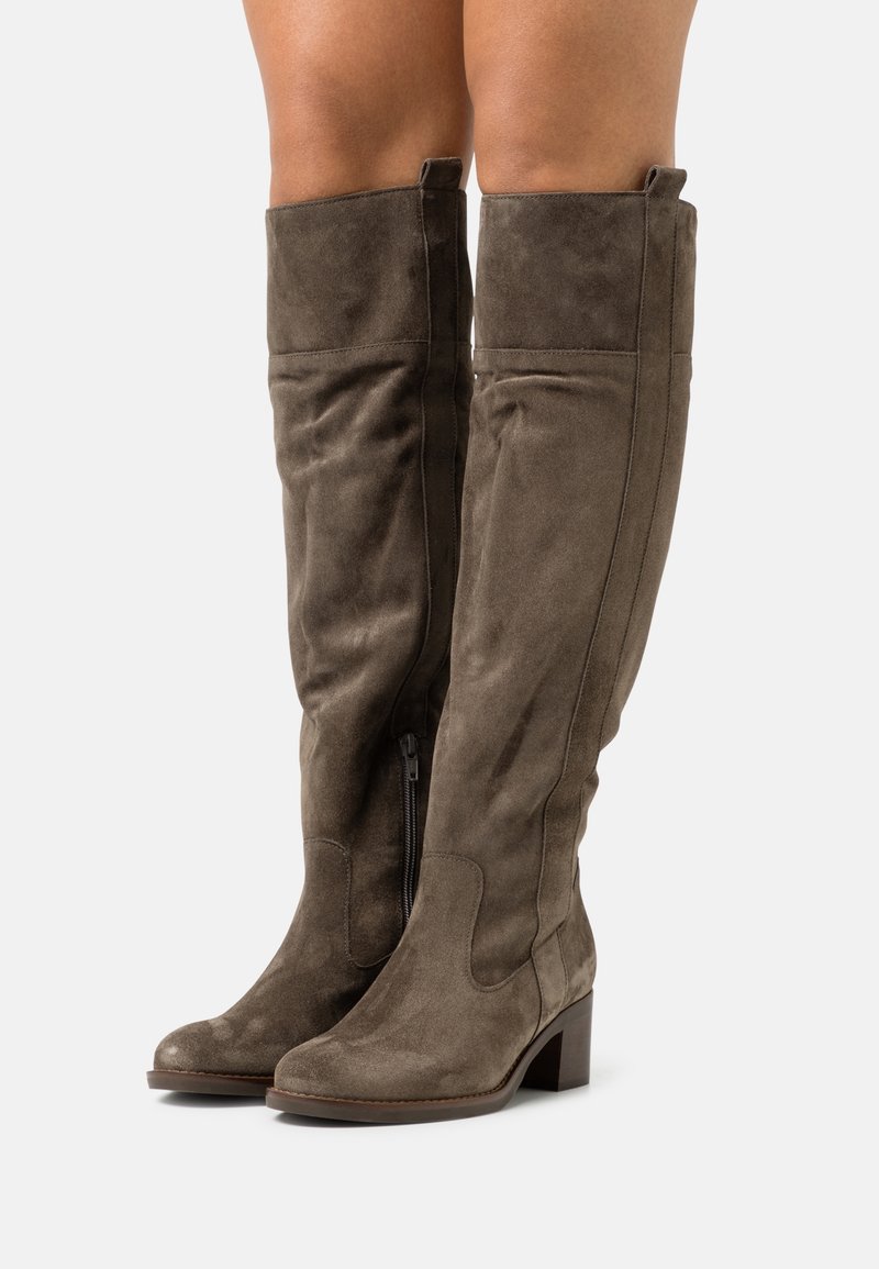 Bottes montantes en daim vert olive avec un bout carré et un talon bloc. Elles possèdent une fermeture éclair latérale et une texture lisse.