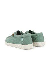 Zapatillas de lona verdes con un acabado texturizado, suelas de goma blancas y un pequeño logo de acento cerca del talón. Diseñadas con una forma redondeada.