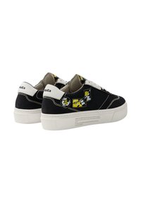 Baskets noires en toile avec semelles en caoutchouc blanches. Présentent des accents graphiques jaunes et des détails cousus. Comprend un logo sur le talon et sur le côté.