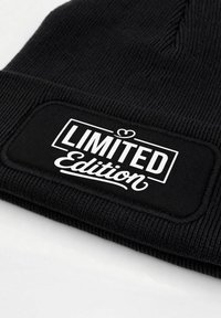Black knit beanie featuring a rectangular patch with the text "LIMITED Edition" in white, showcasing ribbed texture and folded design.