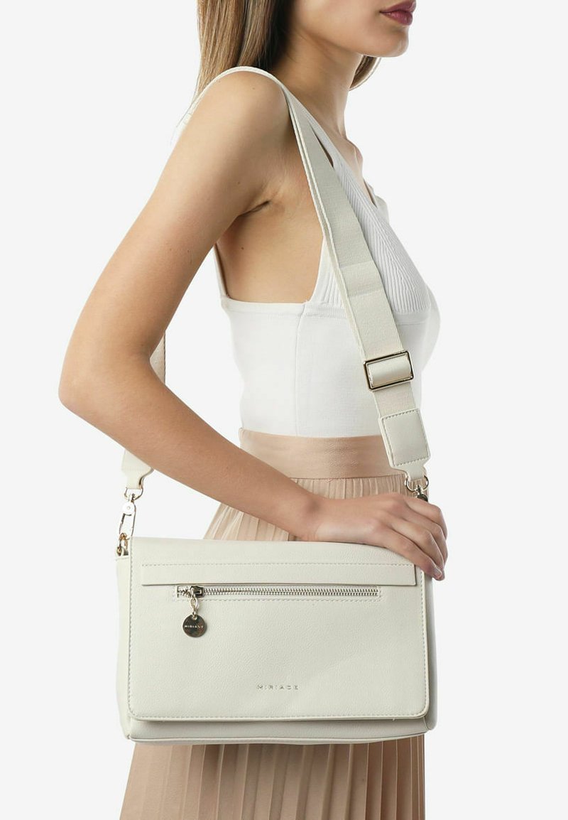 Hvid læder crossbody taske med justerbar rem, der har en frontlomme med lynlås, glat tekstur og en diskret brandingdetalje.