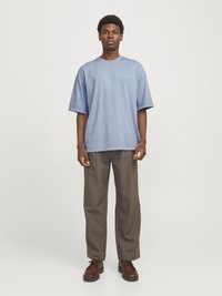 Lysblå oversized t-shirt med korte ærmer og rund hals, parret med løstsiddende brune bukser og mørkebrune snørestøvler.