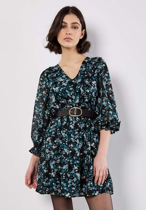 Schwarzes Blumenkleid mit türkisfarbenen und weißen Blumen, V-Ausschnitt, Puffärmeln und einem schwarzen Gürtel. Der Stoff ist leicht und strukturiert.
