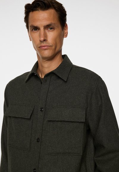 Mörkgrön, texturerad, ullskjortjacka med krage, knappstängning och två bröstfickor med klaffar. Elegant och praktisk design.