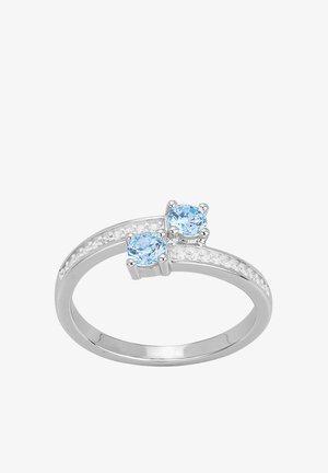 Bague en argent avec deux pierres précieuses rondes bleu clair et petites pierres transparentes réparties le long de la bande fendue sur fond blanc.