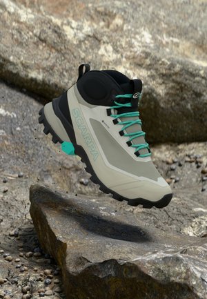 Scarpa Wanderstiefel mit einem beige-schwarzen Design, Gummisohle mit guter Bodenhaftung, türkisfarbenen Schnürsenkeln und Logodetail an der Seite.