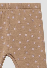 Leggings marron en tissu doux, ornés d'un motif de petits points roses pâles. La ceinture est élastique et les coutures sont visibles le long des bords.