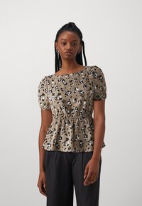 Beige színű peplum felső fekete-fehér állatmintával, rövid puffos ujjakkal és ráncolt derékkal.