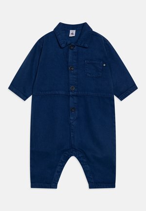 Mørkeblå kortærmet jumpsuit lavet af slidstærkt stof. Den har en krave, frontknapper, lomme og et design med brede ben og afrundede kanter.