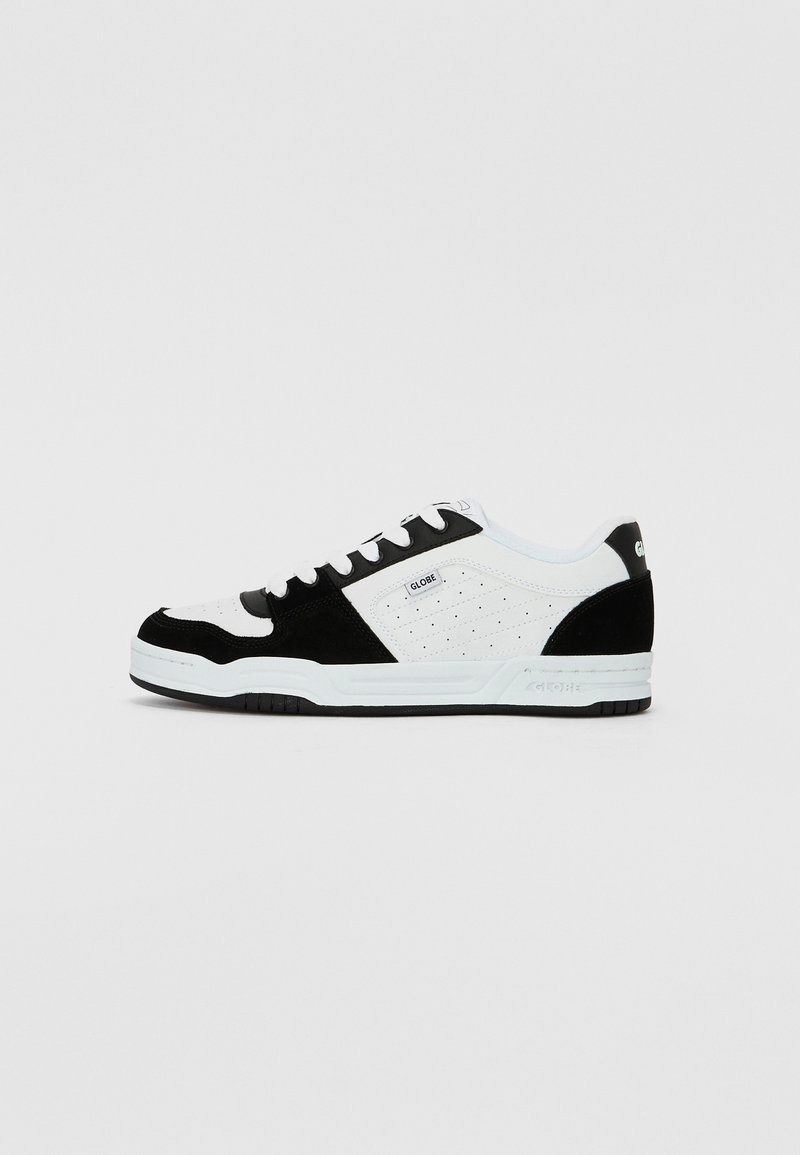 Black and white sneaker with a suede and leather upper, featuring perforations, flat laces, and a textured rubber sole.