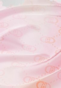 Textil de color rosa claro con una textura suave que presenta un patrón sutil de logotipos superpuestos en un tono de rosa ligeramente más oscuro.