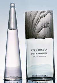 Dwie butelki perfum: jedna wysoka i smukła z srebrną nakrętką, druga prostokątna z teksturowanym srebrnym wieczkiem. Obie mają etykiety z nazwą marki.