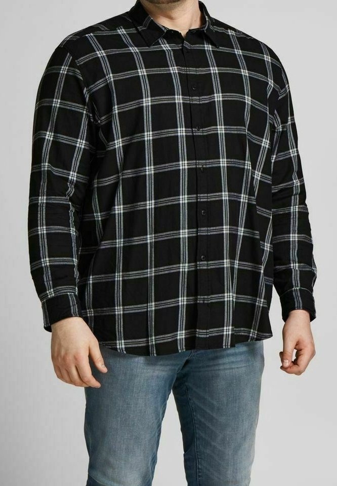 Camicia a maniche lunghe a quadri nera con un motivo a scacchi grigio e blu, abbottonata davanti e colletto aperto. Indossata con jeans azzurri chiari.