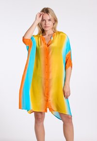 Multikleurige doorschijnende jurk met levendige gradient strepen in geel, blauw en oranje, met een knoopsluiting aan de voorkant en ruime mouwen.
