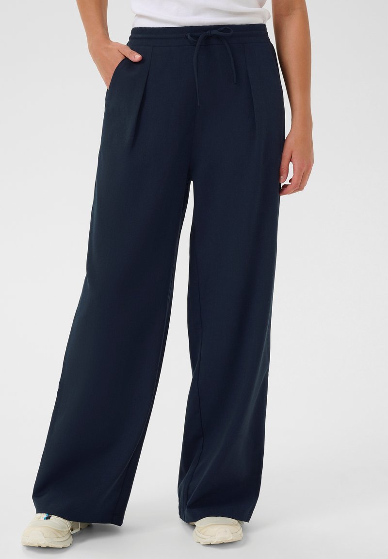 Marinefarbene Weitbein-Hose mit Bund und Kordelzug, ausgestattet mit vorderen Falten und seitlichen Taschen. Glattes Material mit lockerer Passform.