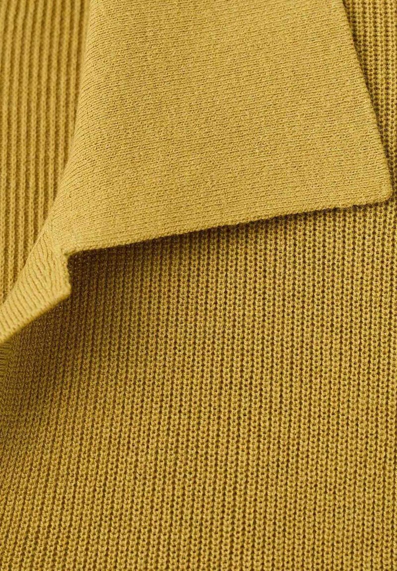 Gestrickter Stoff in Senfgelb, mit einem strukturierten Rippenmuster und glatten Kanten, der Flexibilität und Weichheit zeigt.