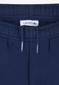 Donkerblauwe joggingbroek met elastische tailleband, trekkoord en Lacoste-label. Zachte stof met een gladde structuur en zonder zichtbare patronen.