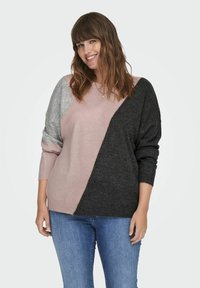 Stickad tröja med en färgblockdesign i ljusrosa, grått och mörkgrå sektioner. Löst sittande och ribbade ärmslut, mjuk textur.