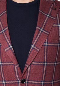 Burgundowa marynarka w kratę, wykonana z teksturowanej tkaniny, z granatowymi liniami i kontrastowym czarnym guzikiem. Nosi się ją na granatowej koszuli.