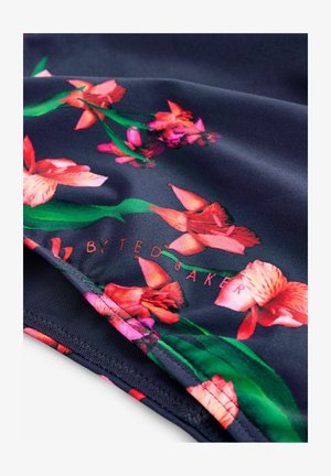 Tmavomodrá kvetinová látka s živými ružovými a oranžovými kvetmi, zelenými stonkami a jemným leskom; obsahuje štítok s nápisom „BY TED BAKER“.