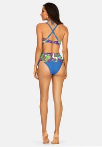 Dwuczęściowy strój kąpielowy z kolorowym kwiatowym i paisley wzorem na górze oraz niebieskimi majtkami. Regulowane ramiączka krzyżują się z tyłu.