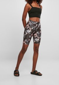 Kvetinové kraťasy na kolo z tmavé látky, s vysokým pasem. Doplněné o přiléhavý černý crop top a černé sandály.