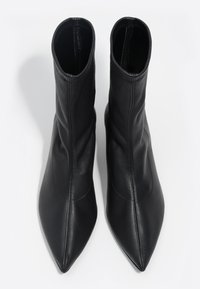 Czarne botki za kostkę wykonane z gładkiej skóry, z ostro zakończonym noskiem i dopasowaną cholewką, ozdobione subtelnymi przeszyciami.