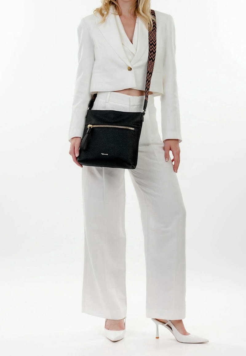 Borsa a tracolla nera in pelle con superficie testurizzata, dettagli in zip dorata e una tracolla decorata. Posizionata su uno sfondo chiaro.