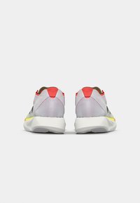 Baskets de sport avec une tige en maille grise respirante, des accents jaune fluo et un onglet de talon rouge. Elles disposent d'une semelle blanche rembourrée et d'un dos texturé.