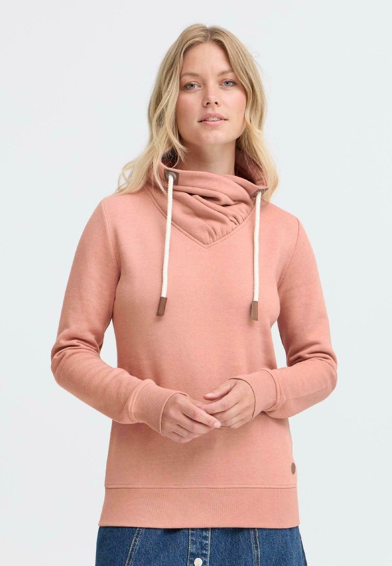 Felpa rosa con cappuccio a imbuto, dotata di lacci e polsini a costine, realizzata in un tessuto morbido, abbinata a una gonna di denim.