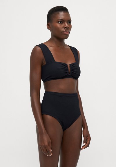 Set di bikini nero con top corto a spalla larga e dettaglio a foro, abbinato a brasiliani a vita alta. Tessuto morbido.