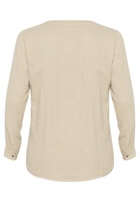 Langärmliges, beiges Oberteil aus leichtem Stoff. Mit Knopfmanschetten und abgerundetem Saum. Schlichtes, strukturiertes Design ohne Muster.