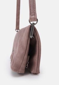 Rosa mockaväsk med en mjuk textur, med ett metallspänne och en platt form. Axelremmen är justerbar och fäst vid silverfärgad hårdvara.