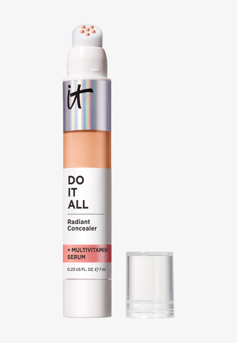 Bâton de correcteur avec des points de crème beige clair sur un applicateur en éponge, étiqueté "Do It All Radiant Concealer + Multivitamin Serum", avec le capuchon à côté.
