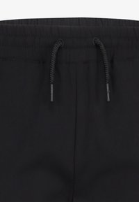 Czarne spodenki z elastycznym pasem, z regulowanym sznurkiem i gładką fakturą. Materiał wydaje się lekki i przewiewny.