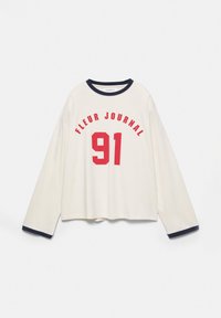 Chemise blanche à manches longues avec bordure marine sur le col et les poignets, présentant le texte rouge "FLEUR JOURNAL" au-dessus d'un grand "91" rouge sur le devant.