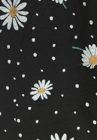 Schwarzer Stoff mit weißen Gänseblümchen mit gelben Blütenmitten und grünen Stielen, durchsetzt mit kleinen weißen Punkten in einem sich wiederholenden Muster.