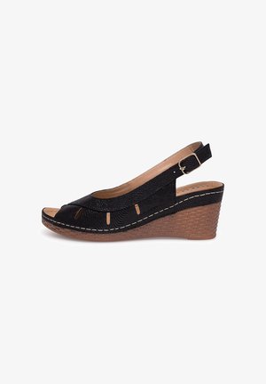Czarna sandałka na koturnie z odkrytym palcem i paskiem z tyłu. Górna część z teksturowanej tkaniny z wycięciami, przeszyciami i plecionym obcasem.