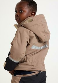 Bruine hoodie-jack met een reflecterende strip, met een zachte textuur, ritszakken en een contrasterend zwart ondergedeelte.
