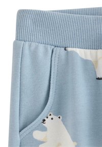 Lyseblå sweatpants med ribbet talje, med en lomme og design af isbjørn. Blødt stof med en glat tekstur.
