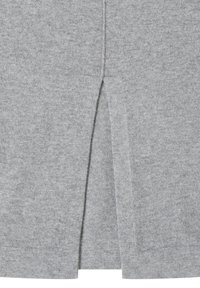 Gros plan d'un tissu tricoté gris clair avec un détail d'ouverture centrale au dos et des lignes de couture visibles.