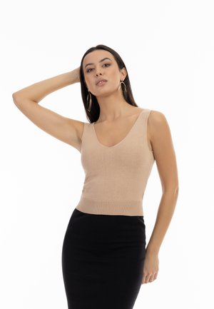 Nude sleeveless top with a deep V-neckline and ribbed texture, paired with a black fitted skirt. Simple design, minimalistic style.