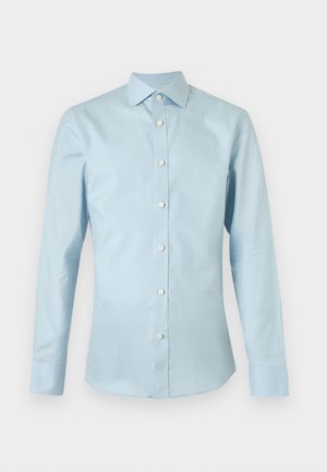 Hele sinine meeste pikkade varrukatega triiksärk valgete nuppude ja terava kraega, kuvatud ühevärvilise tausta ees.