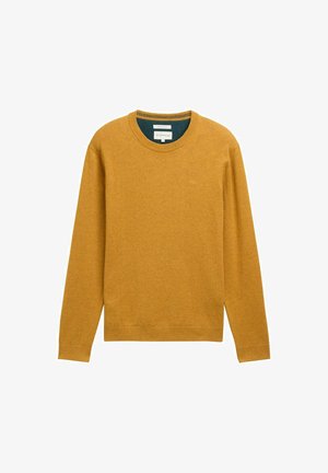 Karamelės geltonos spalvos megztinis su ilgomis rankovėmis ir apvaliu iškirpimu. Pagamintas iš minkštos medžiagos, turi banguotas apdailas ir nedidelį logotipą ant krūtinės.