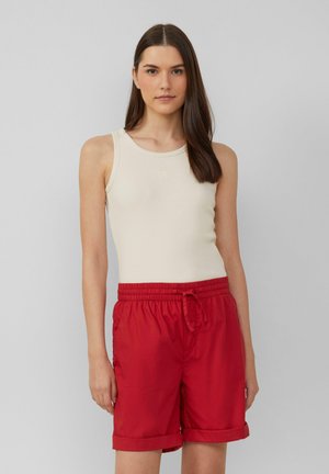 Beige geribbelde tanktop met ronde halslijn en rode shorts met trekkoord, voorzien van een elastische tailleband, omgeslagen mouwen en een gladde textuur.