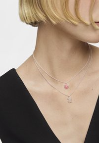 Collares en capas de plata con charms colgantes en rosa y transparente, con forma de flores, acabado suave y cadenas delicadas.